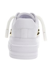 Baskets blanches avec un dessus en cuir lisse, semelle plateforme texturée et lacets blancs tressés. Présente des accents dorés sur les côtés.