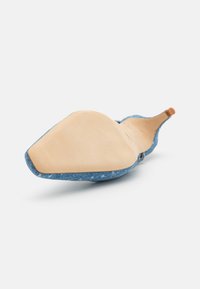 Pointed-toe blue denim shoe with a beige leather sole. Features a slight heel and a smooth, textured upper with stitching detail.