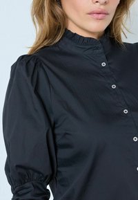 Zwarte knoopblouse met een hoge gerimpelde kraag, gatherd pofmouwen en zilveren knopen, gemaakt van een soepele, lichte stof.