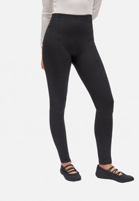 Leggings negros de cintura alta con acentos de panel texturizado. Tejido suave con un diseño ajustado. Combinados con zapatos planos negros.