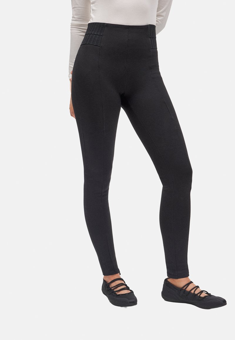 Leggings negros de cintura alta con acentos de panel texturizado. Tejido suave con un diseño ajustado. Combinados con zapatos planos negros.