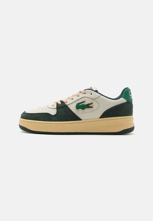 Zapatillas Lacoste con una combinación de cuero blanco y ante verde, featuring cordones rosas, logo bordado y una suela gruesa en color marrón claro.