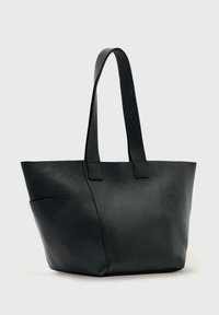 Sac fourre-tout en cuir noir avec une texture douce, une forme effilée, des poignées doubles et un design angulaire. Présente des détails de couture minimalistes.