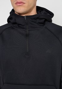 Czarna bluza z kapturem na zamek, wykonana z teksturowanej tkaniny, z wysokim kołnierzem, z wytłoczonym logo na klatce piersiowej oraz gładkim zamkiem.