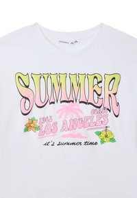T-shirt bianco in cotone con testo multicolore che legge "SUMMER COAST LOS ANGELES" e grafiche floreali di hibiscus e arancio.