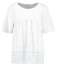 Hvid bomuldsbluse med korte ærmer, der har folder ved udskæringen og lyseblåt broderi langs kanten.