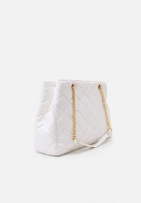Sac à main blanc matelassé avec des chaînes en or, présentant une forme structurée et une texture lisse, mettant en valeur des motifs en diamant diagonaux.