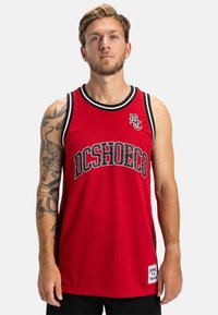 Červená basketbalová dres s priehľadnou tkaninou, čiernym rámom okolo výstrihu a otvorov na rukávy, a na prednej strane je potlačený nápis "DCSHOECO".