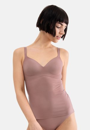 Frau mit kurzen dunklen Haaren, die eine mauve nahtlose Camisole und passende Unterwäsche trägt, schaut nach unten und zur Seite vor einfachem Hintergrund.