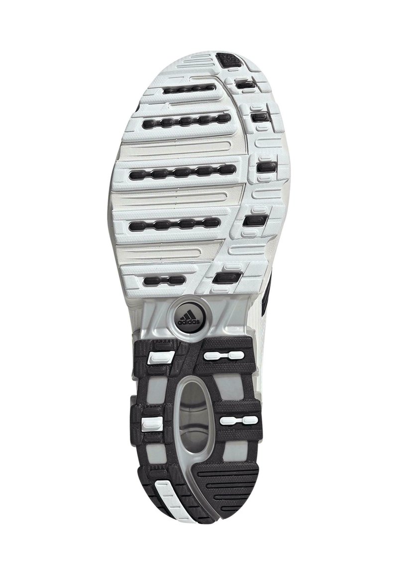 Sohle eines weißen und schwarzen Adidas-Sneakers mit strukturierten Grip-Mustern und einem transparenten ovalen Bereich nahe der Ferse.