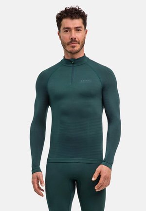 Eng anliegendes Langarmoberteil aus dehnbarem, strukturiertem, dunkelgrünem Stoff. Verfügt über einen hohen Kragen mit einem Viertelreißverschluss und dezentes Branding auf der Brust.