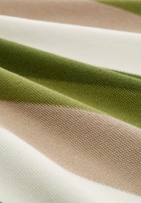 Gewebter Stoff in grünen, beigen und weißen Streifen, mit einer strukturierten Oberfläche, einem einheitlichen Muster und einer glatten, robusten Beschaffenheit.