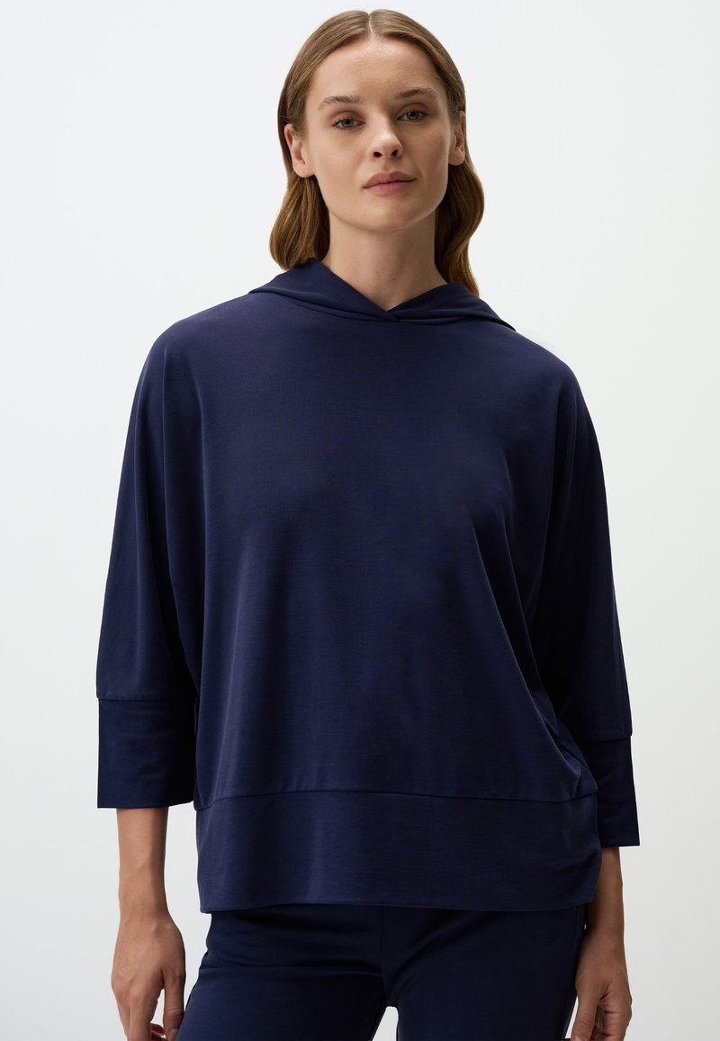 Felpa con cappuccio blu navy, maniche a tre quarti, vestibilità ampia e tessuto strutturato. Presenta una tasca frontale e un orlo arrotondato.