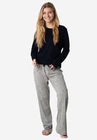 Haut à manches longues bleu marine associé à un pantalon de pyjama gris clair avec un motif floral coloré. Design doux et décontracté.