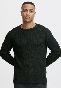 Dark green knitted sweater with a textured pattern, round neckline, and long sleeves, featuring ribbed cuffs and hem.