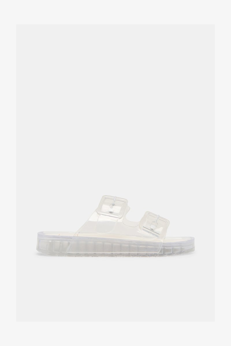 Sandale transparente en plastique avec deux boucles réglables et une semelle claire nervurée, vue de profil sur un fond blanc.