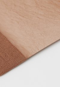 Nude-farvet stof med en glat satinfinish og en tekstureret brun sektion. Overgangen er synlig ved sømmen, hvilket viser kontrasterende teksturer.