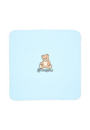 Copertina azzurra da neonato con un’illustrazione centrale di un orsacchiotto e la parola Moschino sotto l’orsetto.