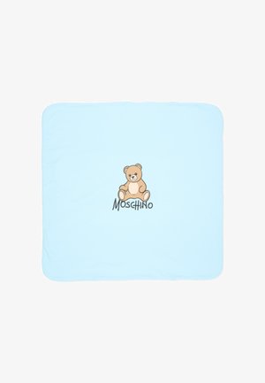 Couverture pour bébé bleu clair avec une illustration centrée d’un ours en peluche et le mot Moschino en dessous de l’ours.