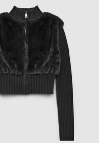 Schwarzer, gekürzter Pullover mit einem gerippten Design und einem Reißverschluss. Der obere Teil hat weiche Kunstfell-Details und lange enganliegende Ärmel.