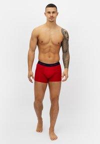 Röda boxershorts med en marinblå midja märkt "HAPPY SHORTS." Tillverkade av mjukt tyg, med en åtsittande passform och inga synliga mönster.