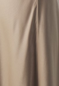 Hame taupe yang terbuat dari satin dengan tekstur halus dan kilau lembut, menampilkan jahitan bersih dan desain yang mengalir.
