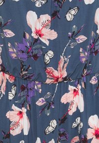 Tissu à motif floral dans des tons de bleu marine, avec des papillons blancs et des fleurs roses, une texture douce et un détail de taille froncée.