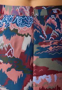 Bunte gemusterte Stoff mit einem abstrakten Design in Pink, Blau und Grün, mit einem verdeckten Reißverschluss auf der Rückseite.