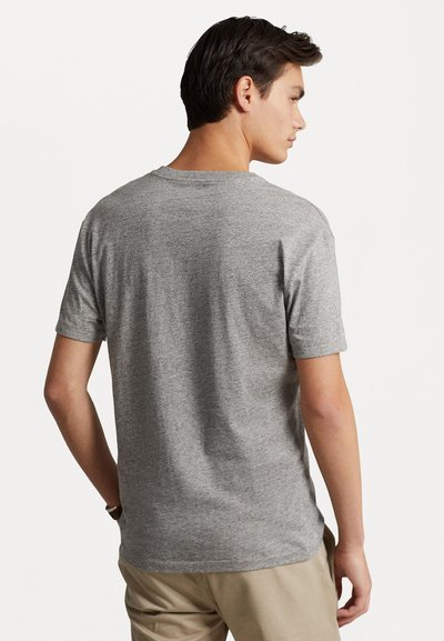 Camiseta gris de manga corta hecha de una tela suave. Presenta un escote redondo y un corte relajado, con una sutil textura contra la piel.