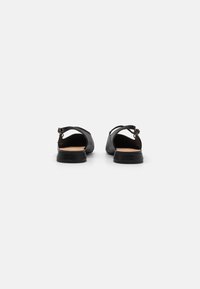 Sandales noires à tige texturée, avec un design à dos ouvert, une sangle réglable et un petit talon en caoutchouc. Convient pour un usage décontracté.