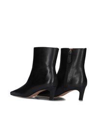 Zwarte leren enkelboots met een puntige neus en een hak van 7,5 cm. Voorzien van een zijrits voor gemakkelijk aan- en uittrekken. Gladde textuur, slank design.
