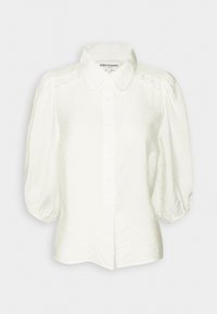 White blouse with a structured collar, puffed sleeves, and textured fabric. Features button closure and delicate lace accents on shoulders.
