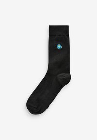 Black sock made of soft fabric, featuring a small blue and yellow monster character embroidered on the outer side. Standard crew length.