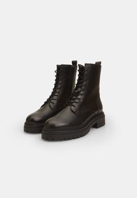 Bottines en cuir noir à lacets avec fermeture éclair latérale, bout rond solide et semelle texturée, présentant une surface lisse et des coutures minimales.
