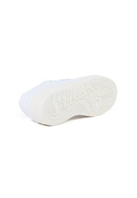 White sneaker with a textured rubber sole. Features a smooth upper and prominent branding on the outsole. Side view highlights rounded shape.