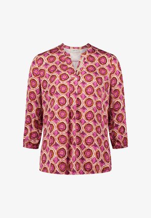 Bluzka w wzory z dekoltem w serek, z rękawami 3/4. Posiada sześciokątne wzory w odcieniach różu, pomarańczy i bieli na jasnym tle.