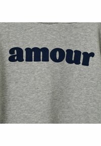 Šedá bavlnená mikina s potlačou "amour" v tučných, námorníckych modrých písmenách. Jemný materiál s okrúhlym výstrihom a bez viditeľných zdobení.