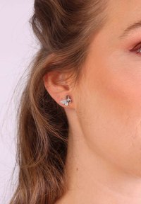 Boucles d'oreilles en argent en forme de papillon ornées de pierres précieuses transparentes, conçues avec des détails délicats et une finition polie sur le métal.
