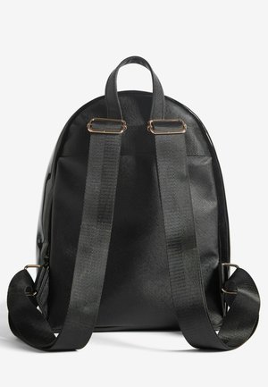 Rucsac negru, realizat dintr-un material sintetic texturat. Are o formă rotunjită, bretele din țesătură ajustabile și accente metalice.