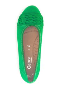 Ballerines plates en daim vert avec un détail tissé au niveau des orteils. Elles présentent une semelle intérieure lisse avec des perforations et une forme de bout arrondi.