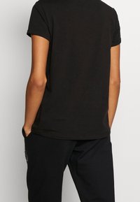 Mustat lyhythihaiset T-paidat, jotka on valmistettu puuvillasta, klassisella pyöreällä kaula-aukolla ja rentolla istuvuudella. Takapuoli on sileä ilman näkyviä grafiikoita.