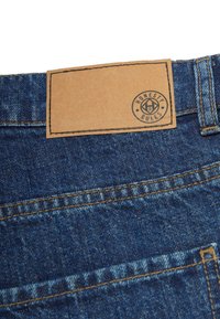 Jeans i denim med en mörkblå tvätt, med en brun läderetikett som är sydd på midjebandet med "HONESTY RULES" präglat.
