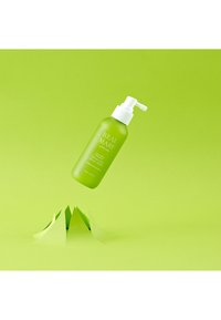 Grön sprayflaska med en vit pump, märkt "REAL MARY" i vit text. Bakgrunden har en ljusgrön yta med lager av grönt papper som accent.