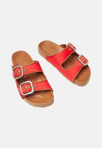 Crvene platnene papuče na punu petu imaju dva široka remena s srebrnim kopčama, prirodnu kožnu uložak i teksturiranu smeđu potplat.