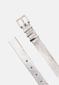 Cintura in pelle argentata metallica con finitura testurizzata, dotata di una fibbia argento e cinque fori per la regolazione. Nome del marchio impresso sul cinturino.