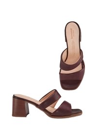 Bruine leren hoge hak slide sandalen hebben twee gekruiste banden, een open hiel en een gebogen blokhak met een gestructureerd oppervlak.