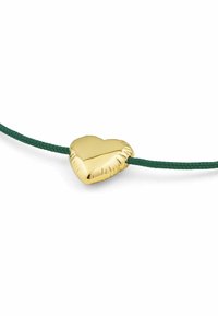 Ciondolo a forma di cuore in oro con bordi texturizzati, attaccato a un cordino intrecciato verde, che presenta una superficie liscia e un design minimalista.