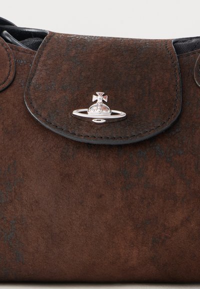 Hnedá semišová klopa kabelky so strieborným logom v tvare orbu a kríža uprostred na prednej strane.