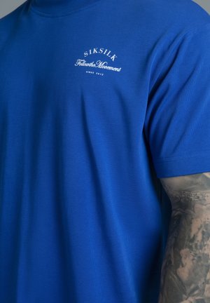 Niebieski bawełniany t-shirt z krótkimi rękawami i okrągłym dekoltem, z białym nadrukiem logo na piersi. Gładka faktura, dopasowany krój.