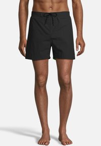 Zwarte zwembroek met een rijgband in de taille, van een effen kleur en lichtgewicht stof. Opvallende groene accenten zijn zichtbaar langs de zoom.